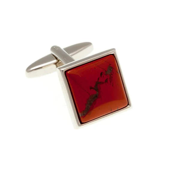 Cufflink with red stone and silver frame on a white background