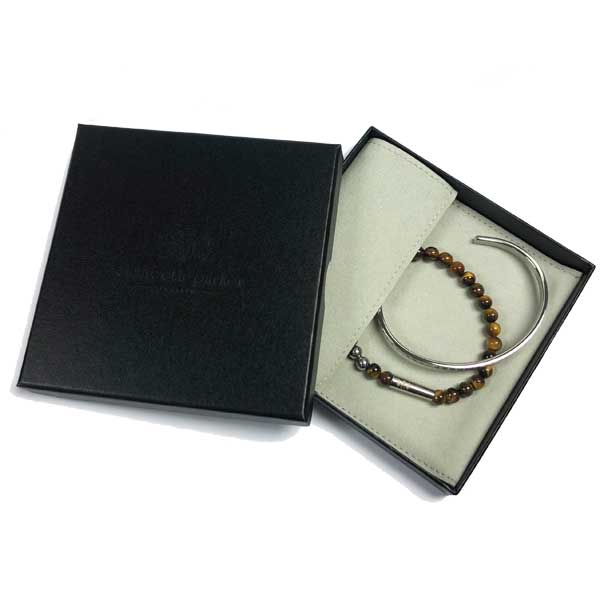 Bracelet with beads and metal bar in a black box on a white background