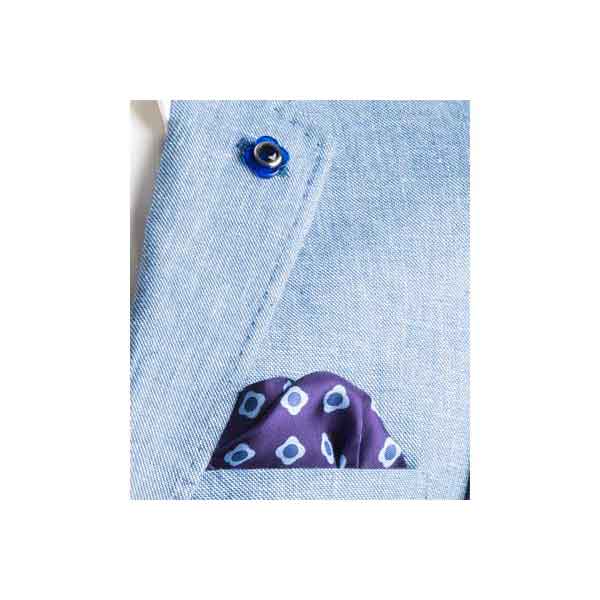 Close-up of a blue denim shirt with a purple pocket square featuring white and blue polka dots.