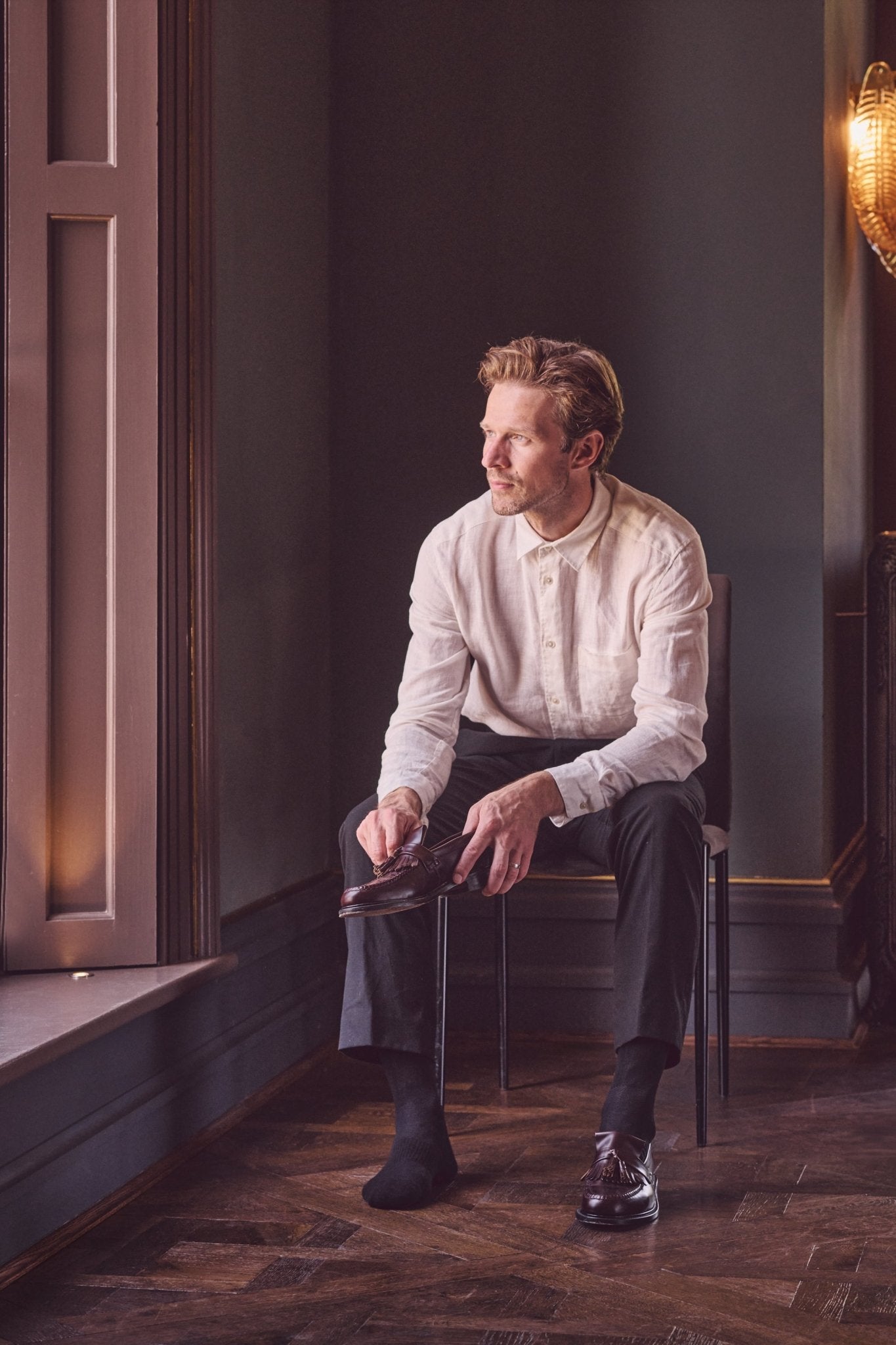 Man sitting on a chair by a window in a dimly lit room