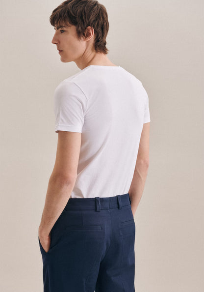 Person wearing a white t-shirt and navy pants against a beige background