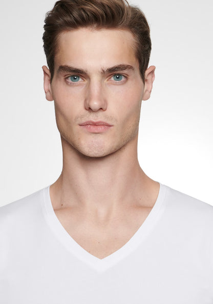 Man wearing a white V-neck shirt against a plain background