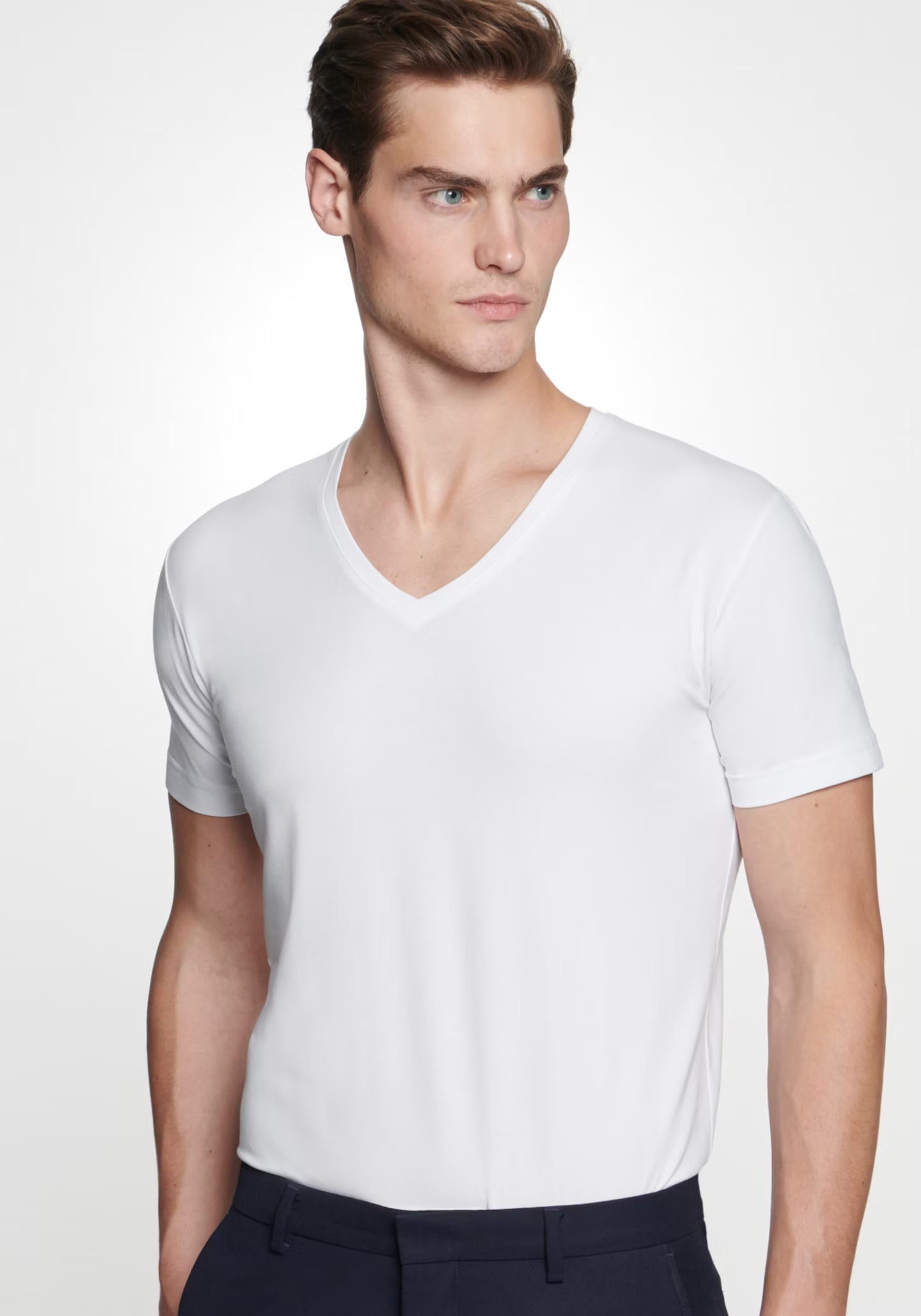 Man wearing a plain white t-shirt against a white background