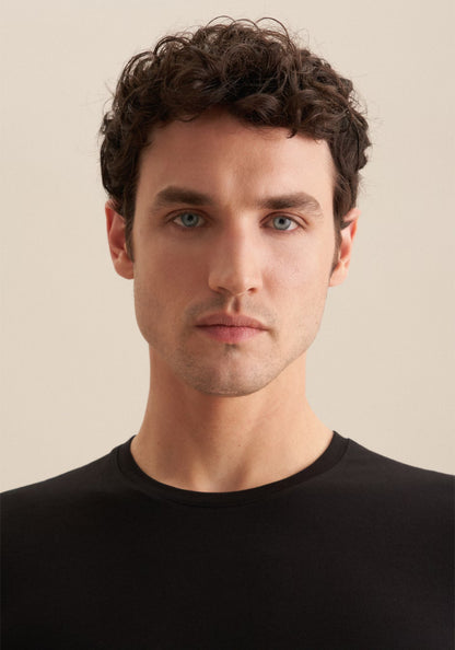 Man wearing a black shirt against a beige background