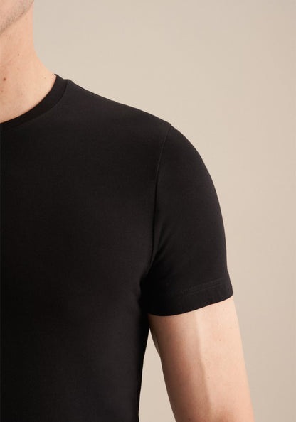 Black t-shirt worn by a person on a beige background
