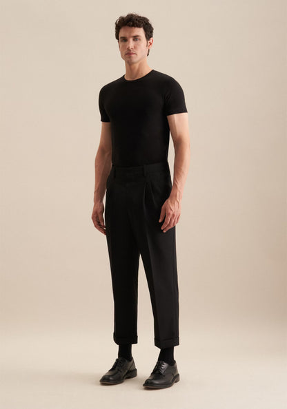 Man wearing a black t-shirt and black pants on a beige background