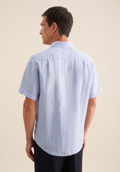 Man wearing a light blue short-sleeve shirt on a beige background