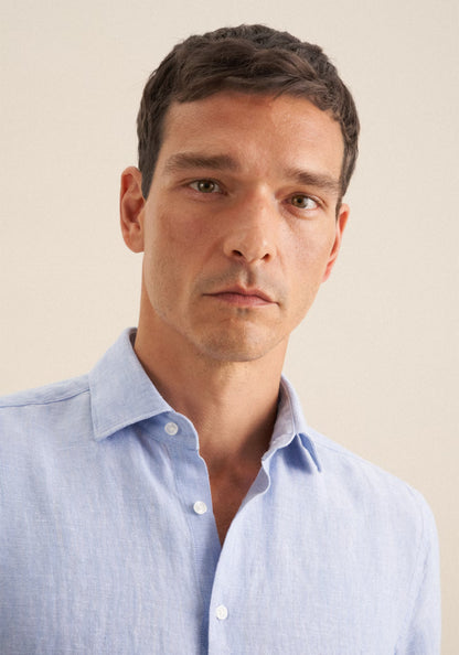Man wearing a light blue shirt against a beige background
