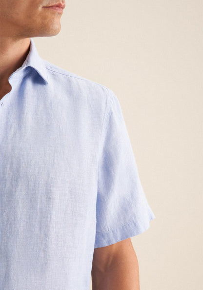 Light blue short-sleeve shirt worn by a person on a beige background
