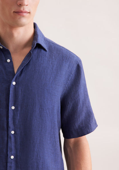 Close-up of a person wearing a blue short-sleeve shirt on a light background