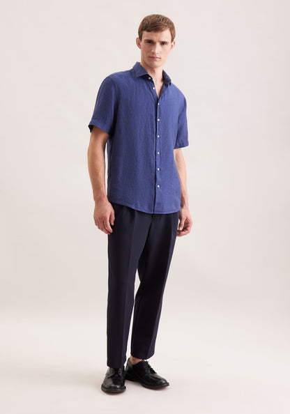 Man wearing a blue short-sleeve shirt and black pants on a white background