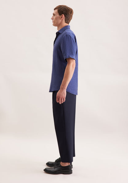 Man wearing a blue shirt and black pants on a white background