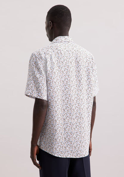 Person wearing a short-sleeve, patterned shirt on a plain background