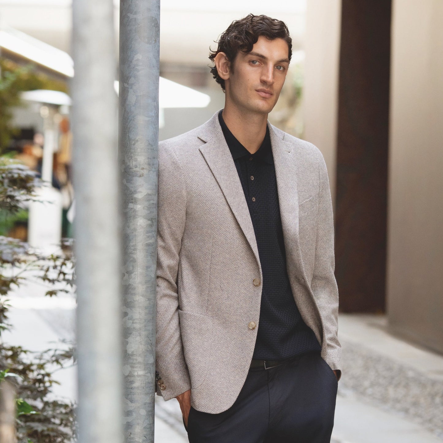 Man in a light gray blazer and black pants standing outdoors.