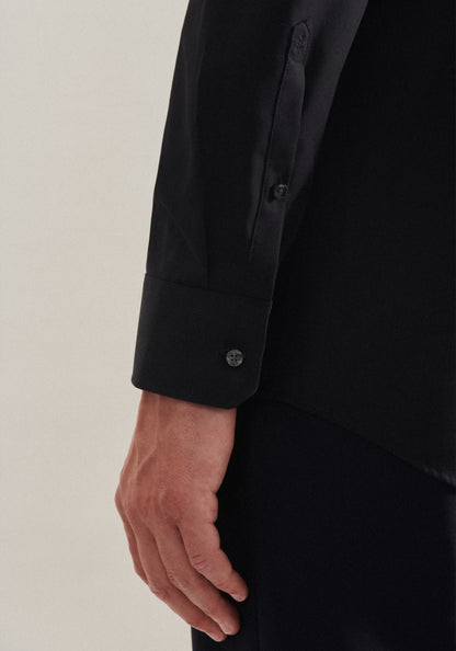 Close-up of a person wearing a black shirt with a beige background