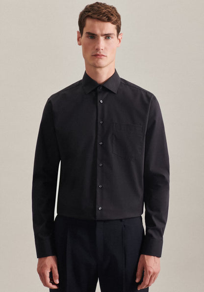Man wearing a black shirt and pants against a plain background