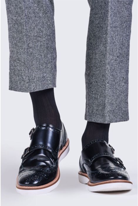 Black leather shoes worn with gray pants and black socks on a white background