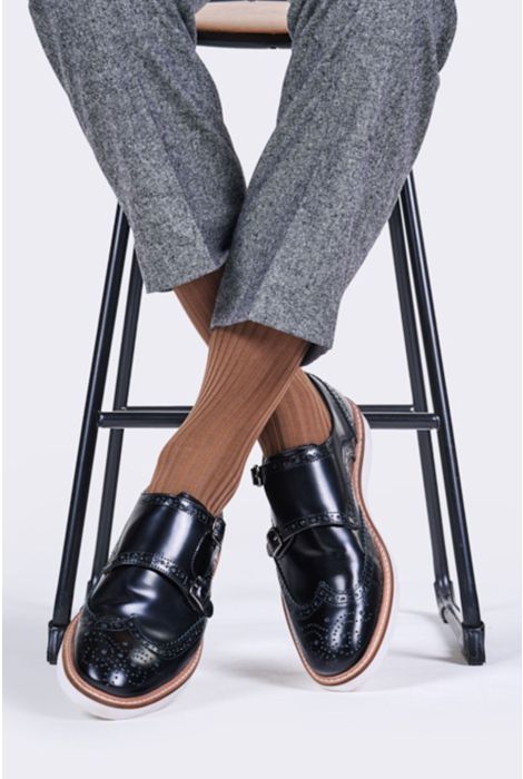 Person wearing black leather shoes with wooden soles on a white background
