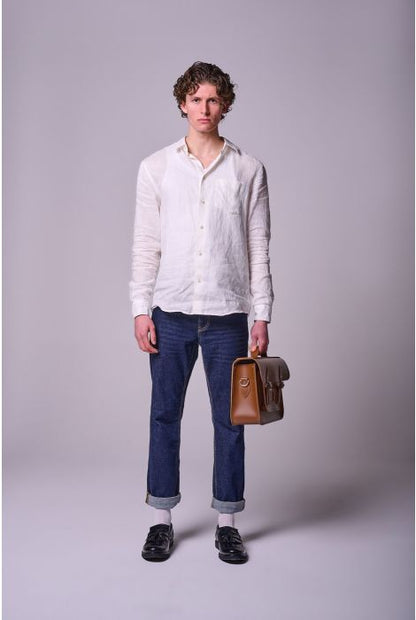 Man wearing a white shirt and blue jeans holding a brown leather briefcase against a plain background