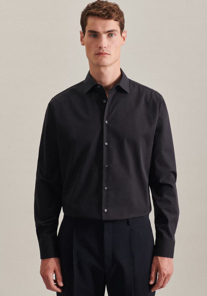 Man wearing a black dress shirt and pants against a neutral background