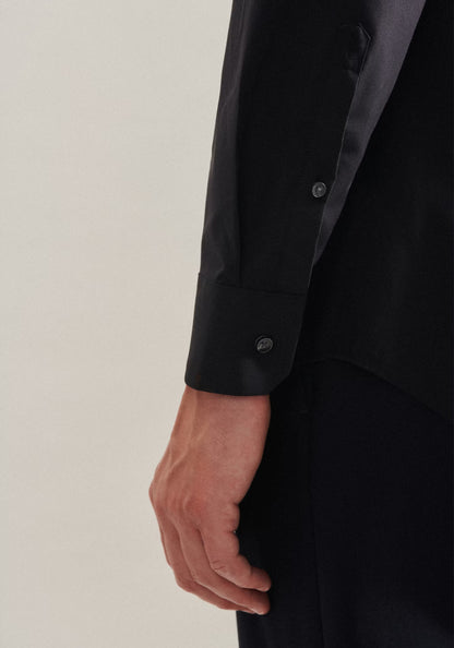 Close-up of a person wearing a black shirt with rolled-up sleeves on a plain background