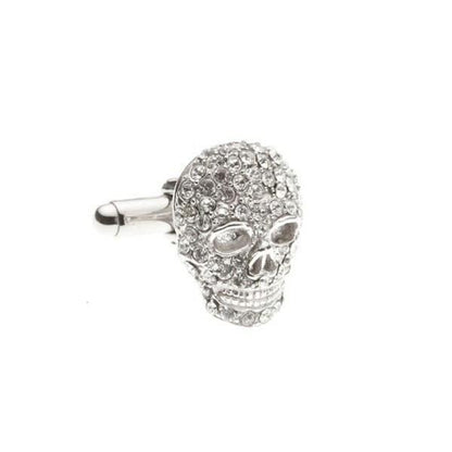Silver skull-shaped cufflink with gemstones on a white background