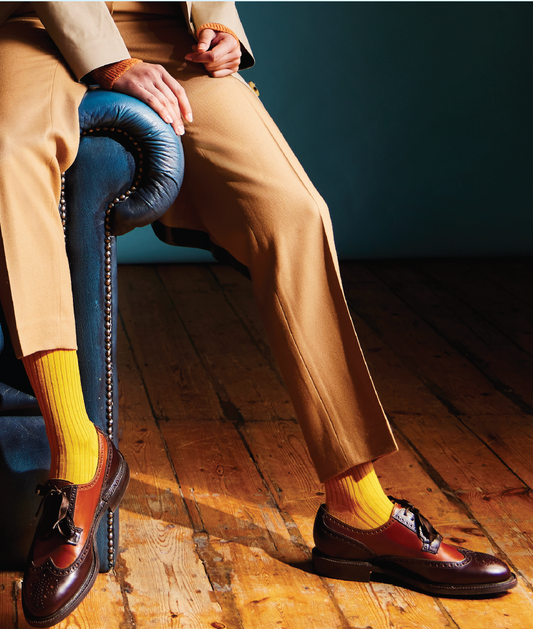 Person wearing tan pants, brown shoes, and yellow socks sitting on a blue chair.