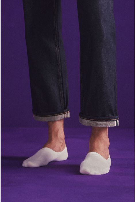 Person wearing black pants and white socks on a purple background