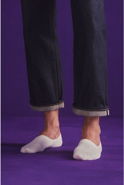 Person wearing black pants and white socks on a purple background