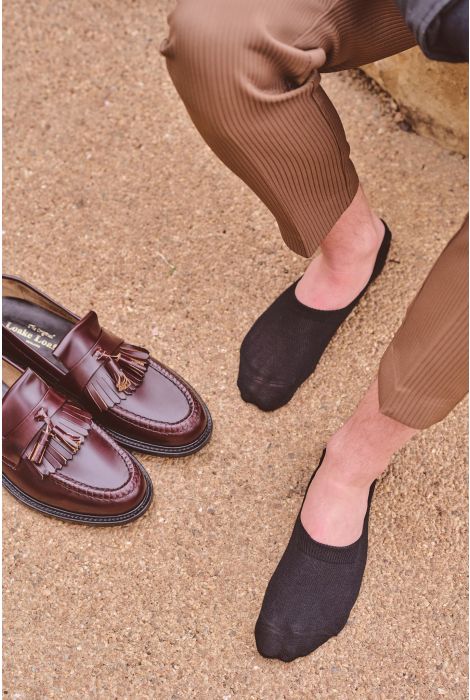 Brown loafers and black flat shoes on a textured surface