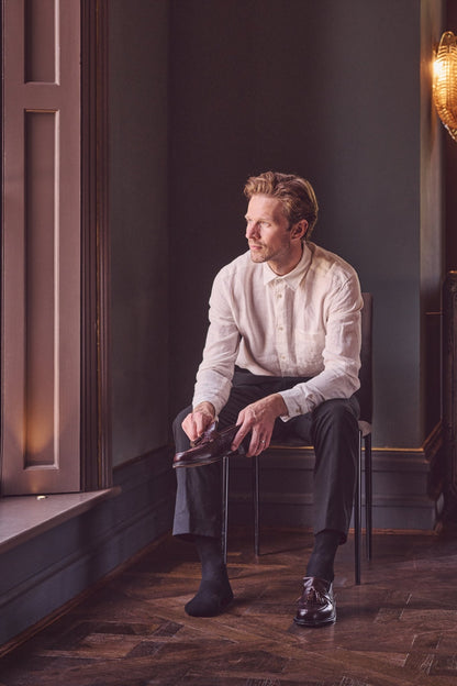 Man sitting on a chair by a window in a dimly lit room