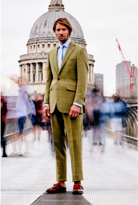 Man in a green suit standing in an urban setting with a blurred background