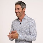 Man wearing a light gray patterned shirt with his hands clasped together.