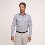 Man wearing a patterned shirt and light pants on a white background