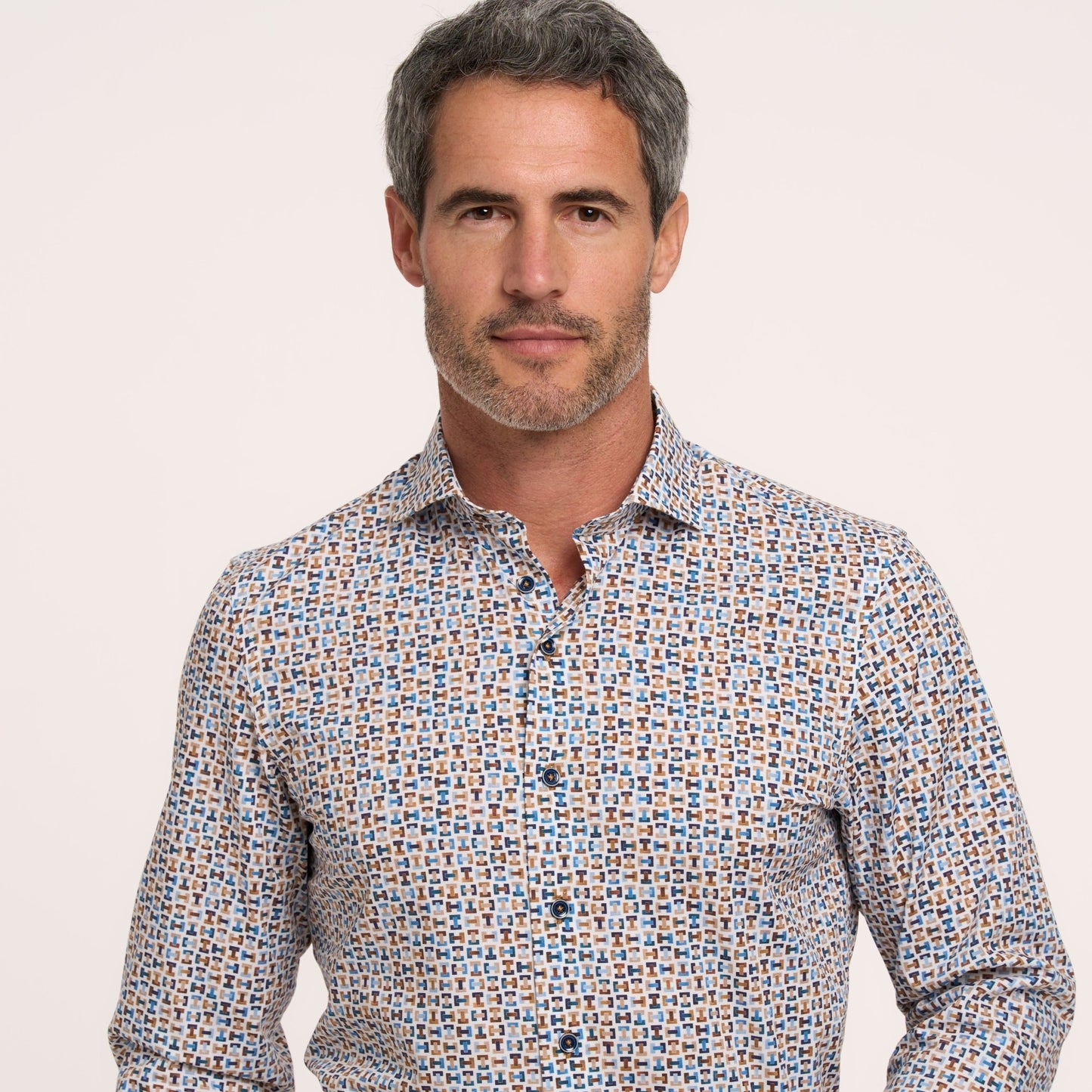 Man wearing a patterned shirt against a plain background