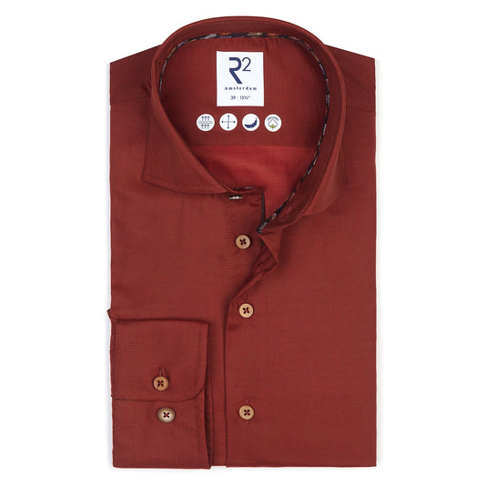 Folded red shirt with a brand label on a white background