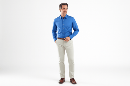 Man wearing a blue shirt and beige pants on a white background