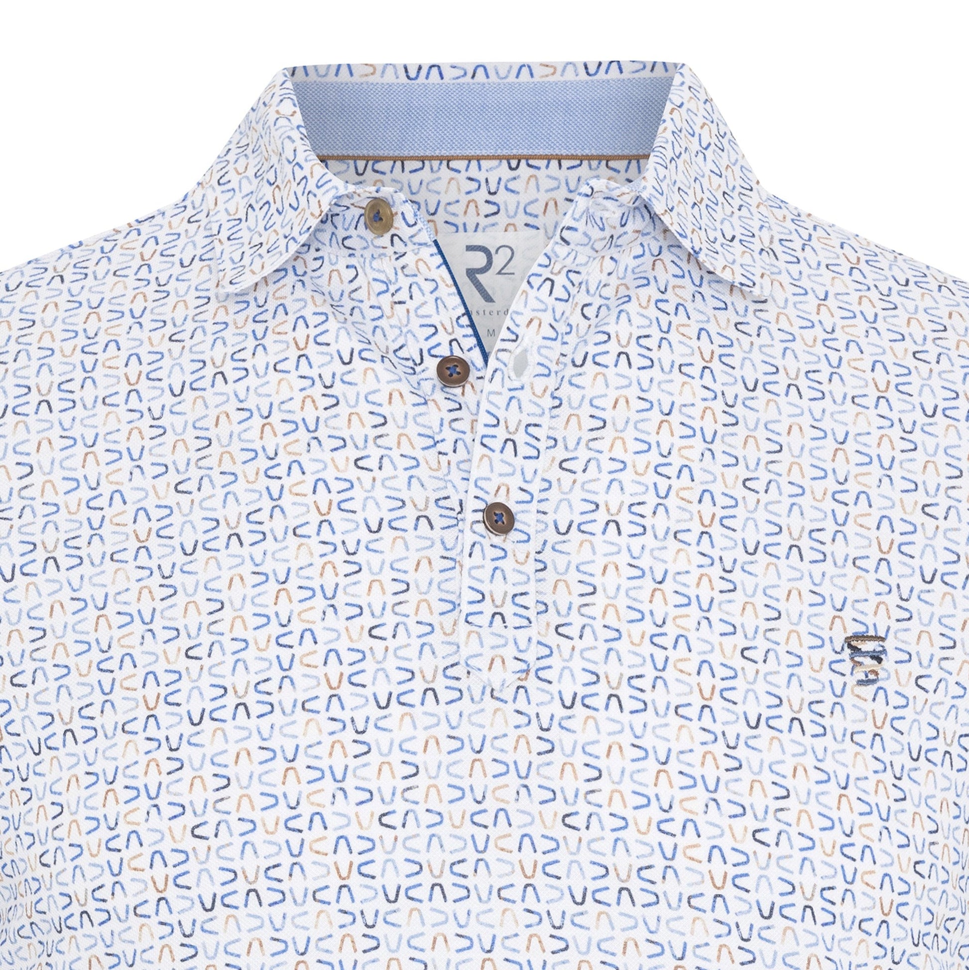 Close-up of a patterned shirt with a brand logo on a white background