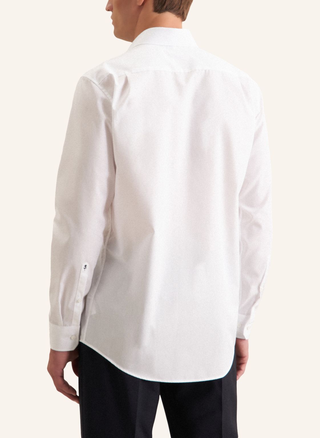 Person wearing a white dress shirt on a plain background