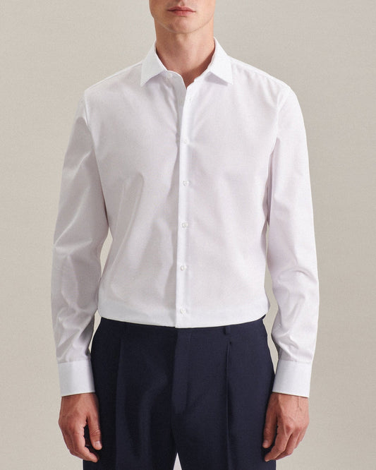 Person wearing a white dress shirt and navy pants against a plain background