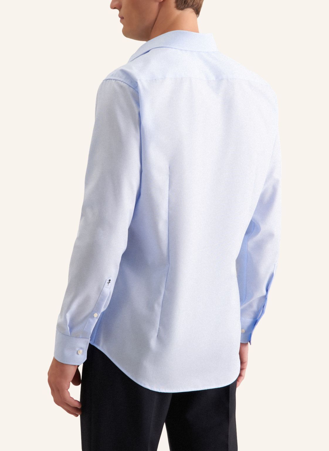 Man wearing a light blue dress shirt with a subtle pattern on a white background