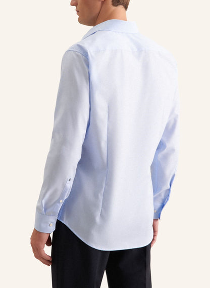 Man wearing a light blue dress shirt with a subtle pattern on a white background