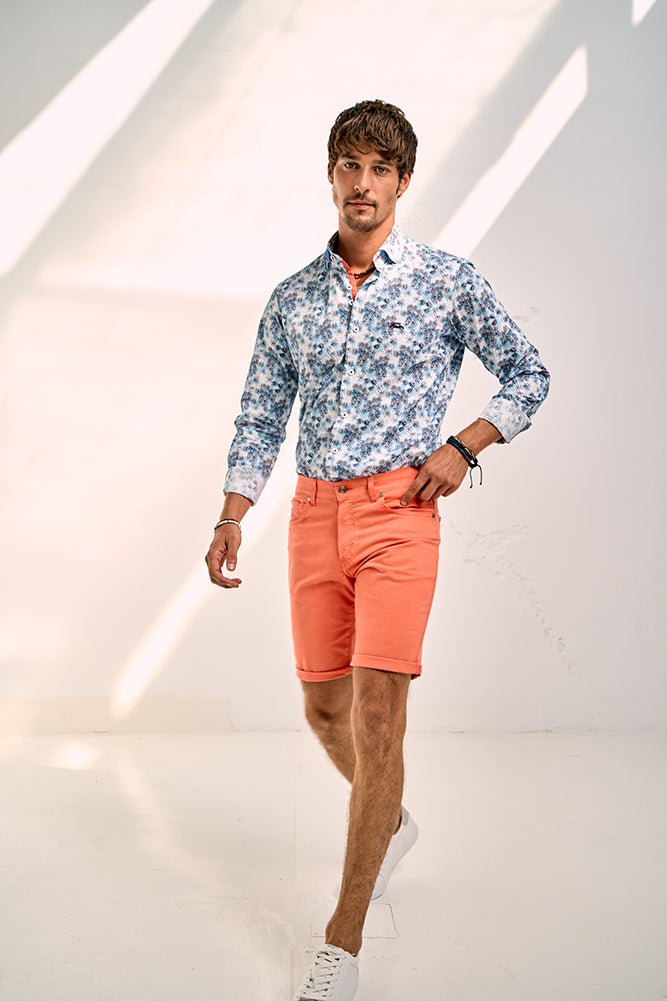 Man wearing a floral shirt and orange shorts against a white background